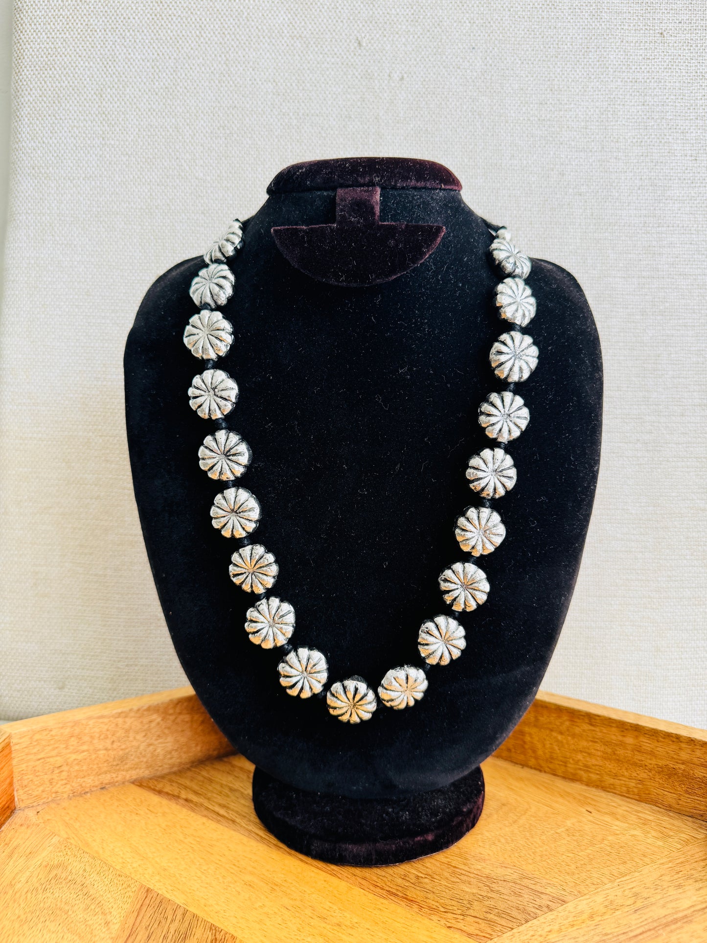 Necklace on a black velvet bust against a light gray background