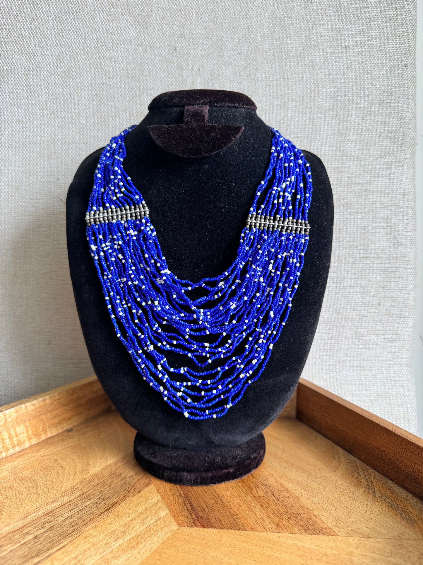 Blue beaded headband on a black hat against a neutral background