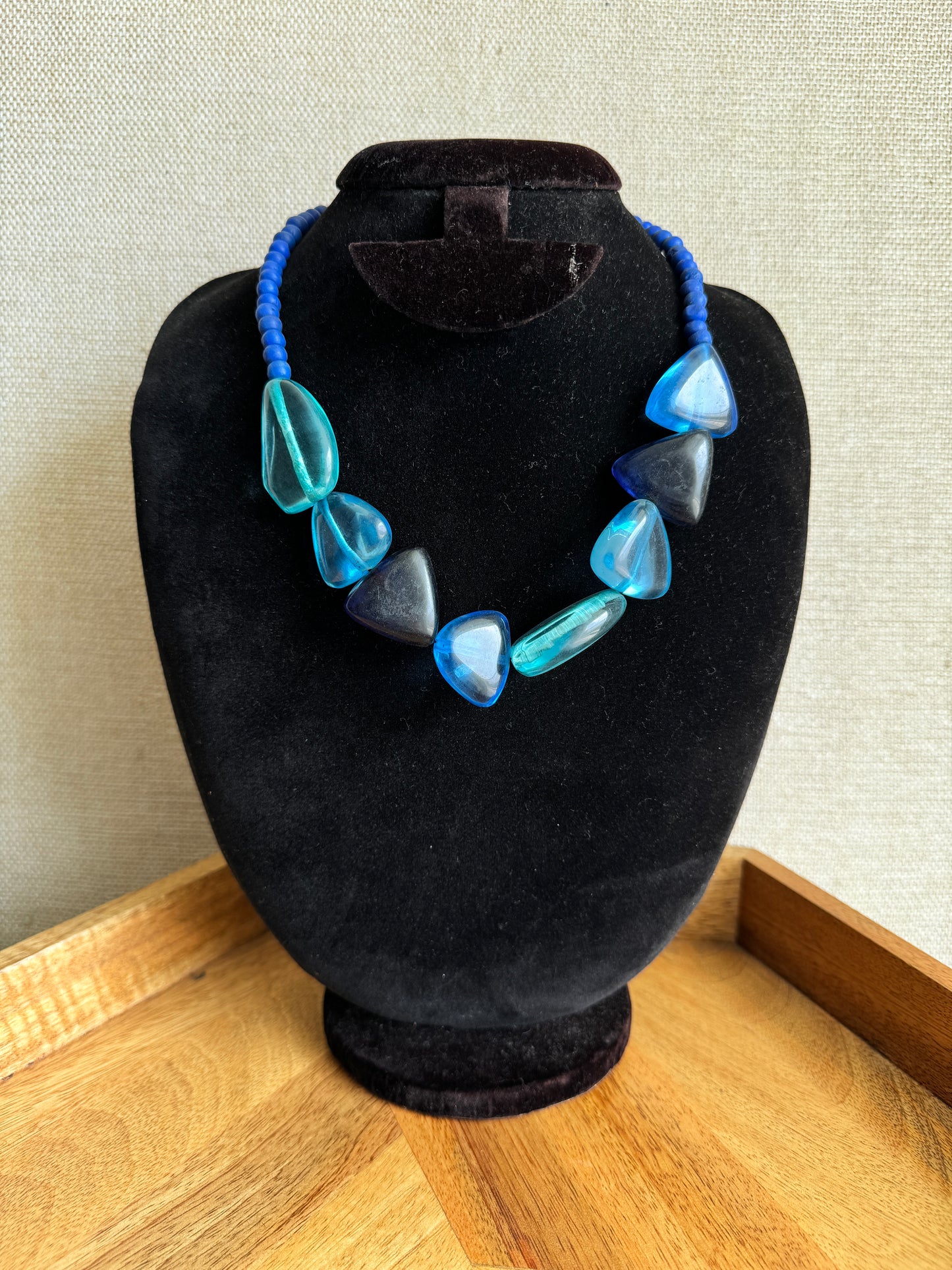 Necklace with blue and clear heart-shaped beads on a black stand.