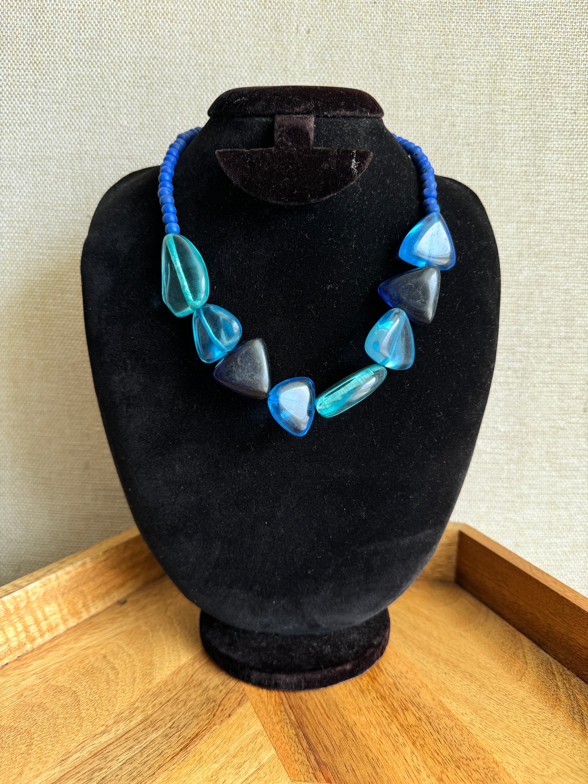 Necklace with blue and clear heart-shaped beads on a black stand.