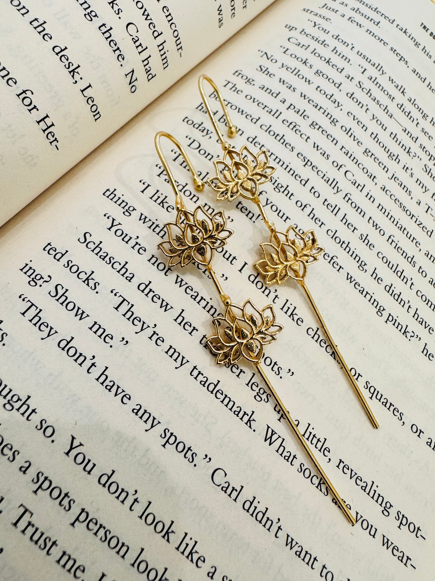 Gold floral earrings on an open book
