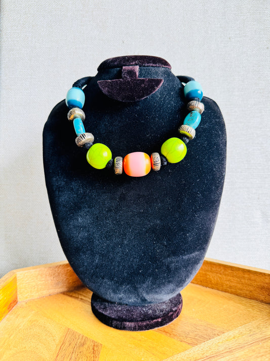 Necklace with colorful beads on a black velvet stand against a light gray background
