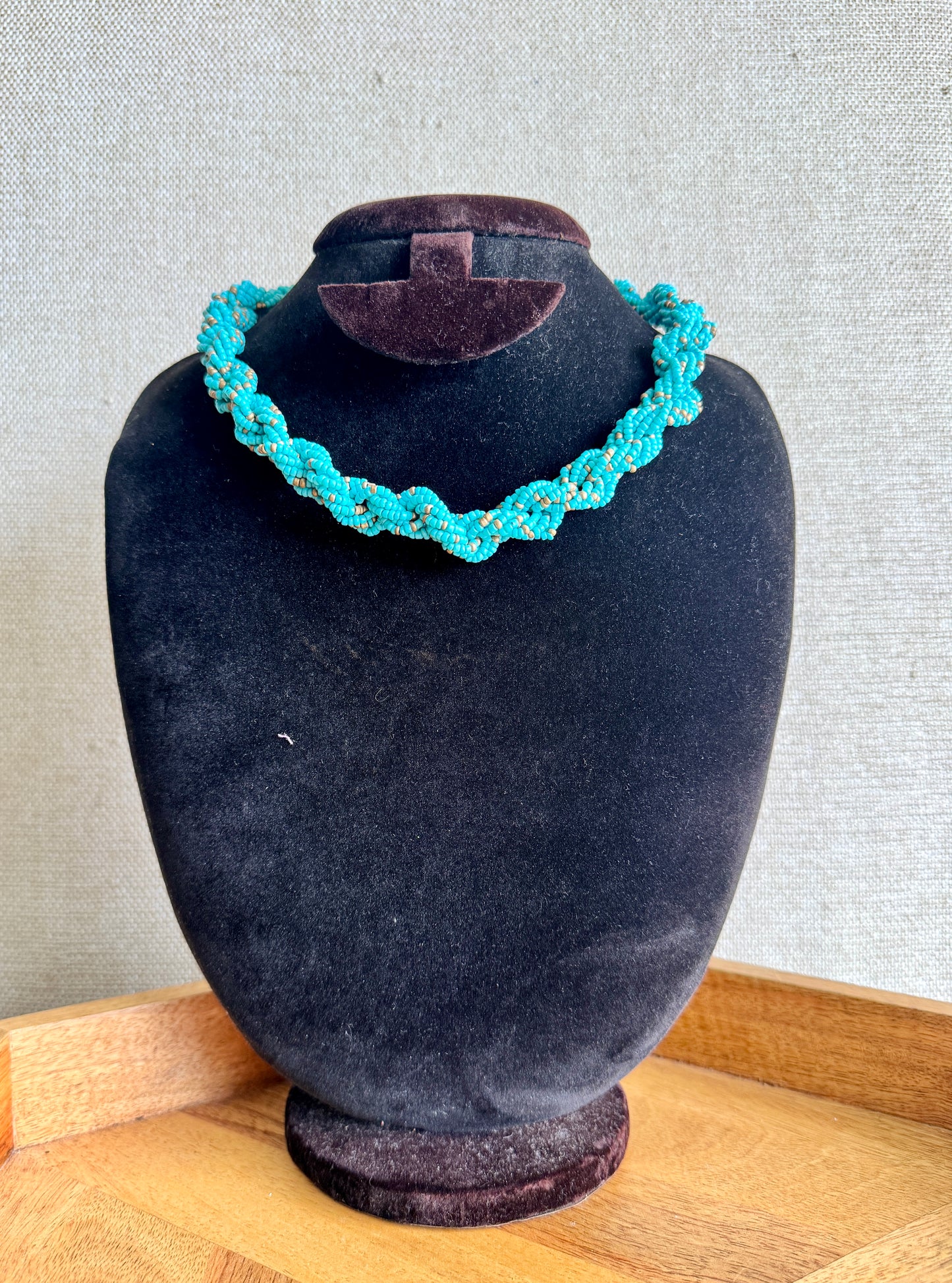 Turquoise beaded necklace on a black velvet mannequin bust against a neutral background